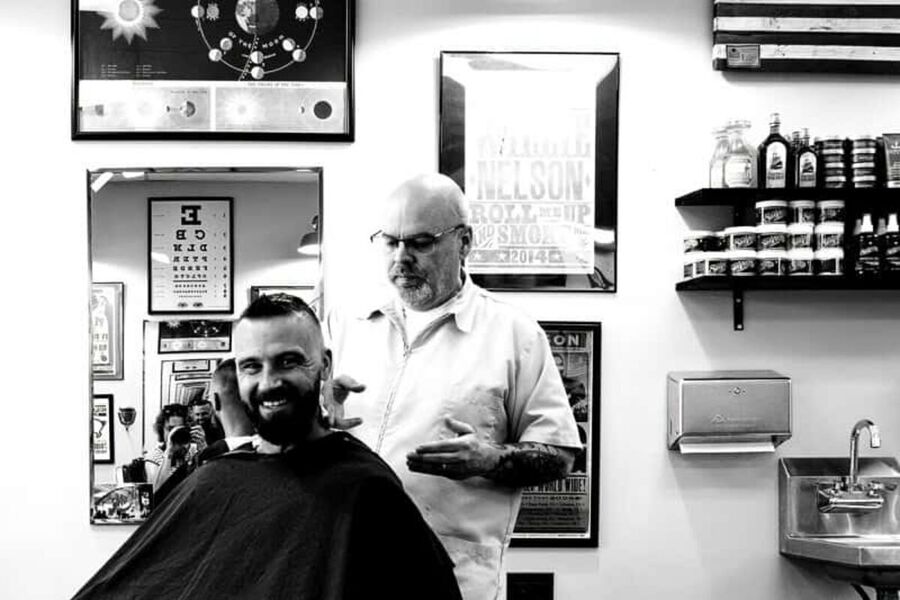 A barber and a smiling client inside Monty's Barber Shop