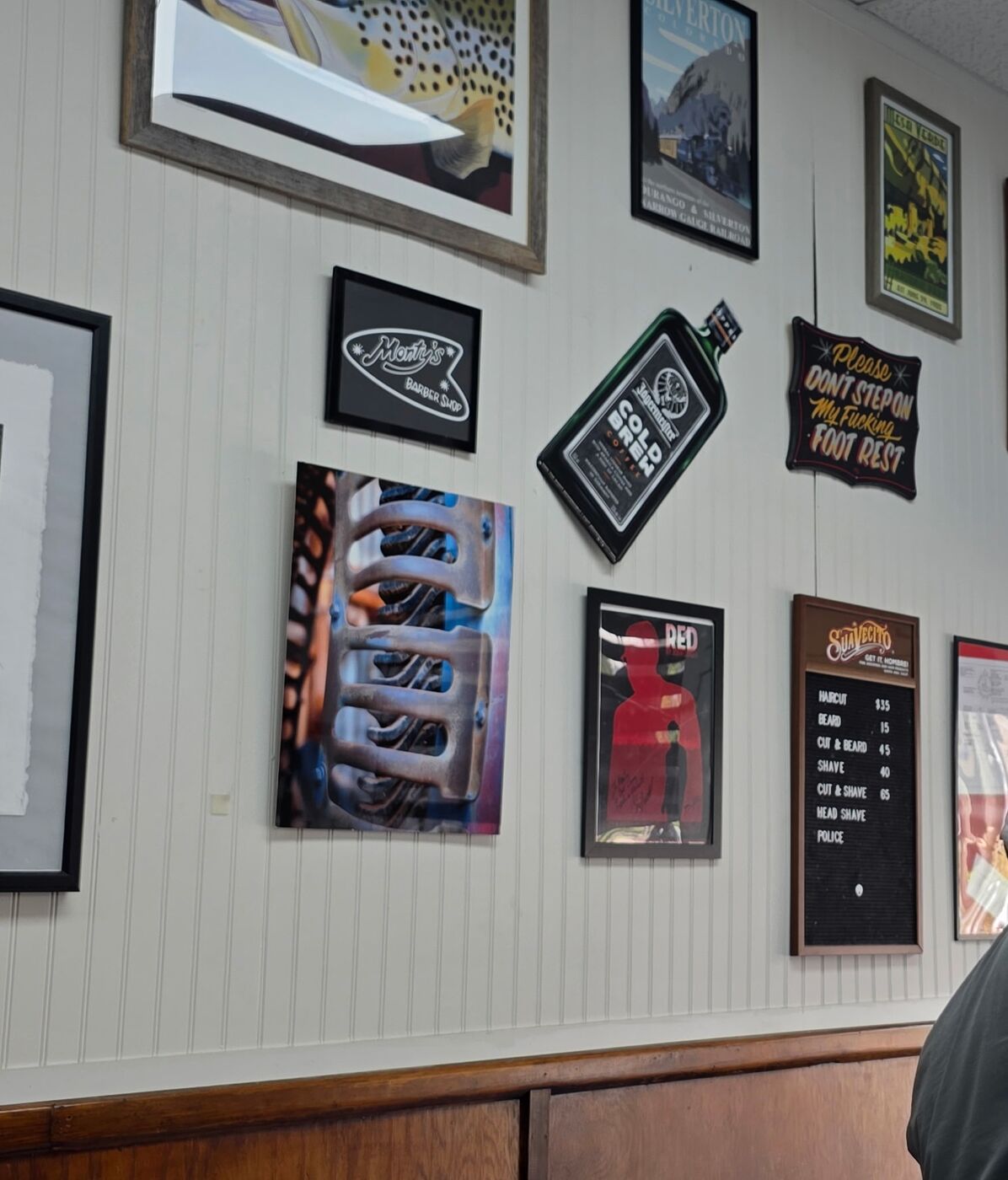 Framed prints and the Monty's Barber Shop sign on the shop wall